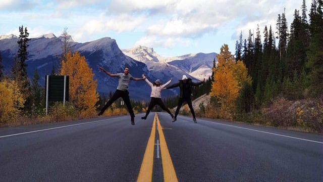 3 amigos saltando en una carretera de Canadá